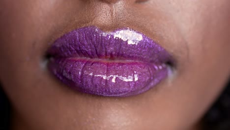 close-up of purple glitter gloss lipstick on woman's lips