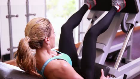 super fit woman using the leg weights machine