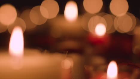 defocused shot of romantic red and white candles with bokeh lighting on black background