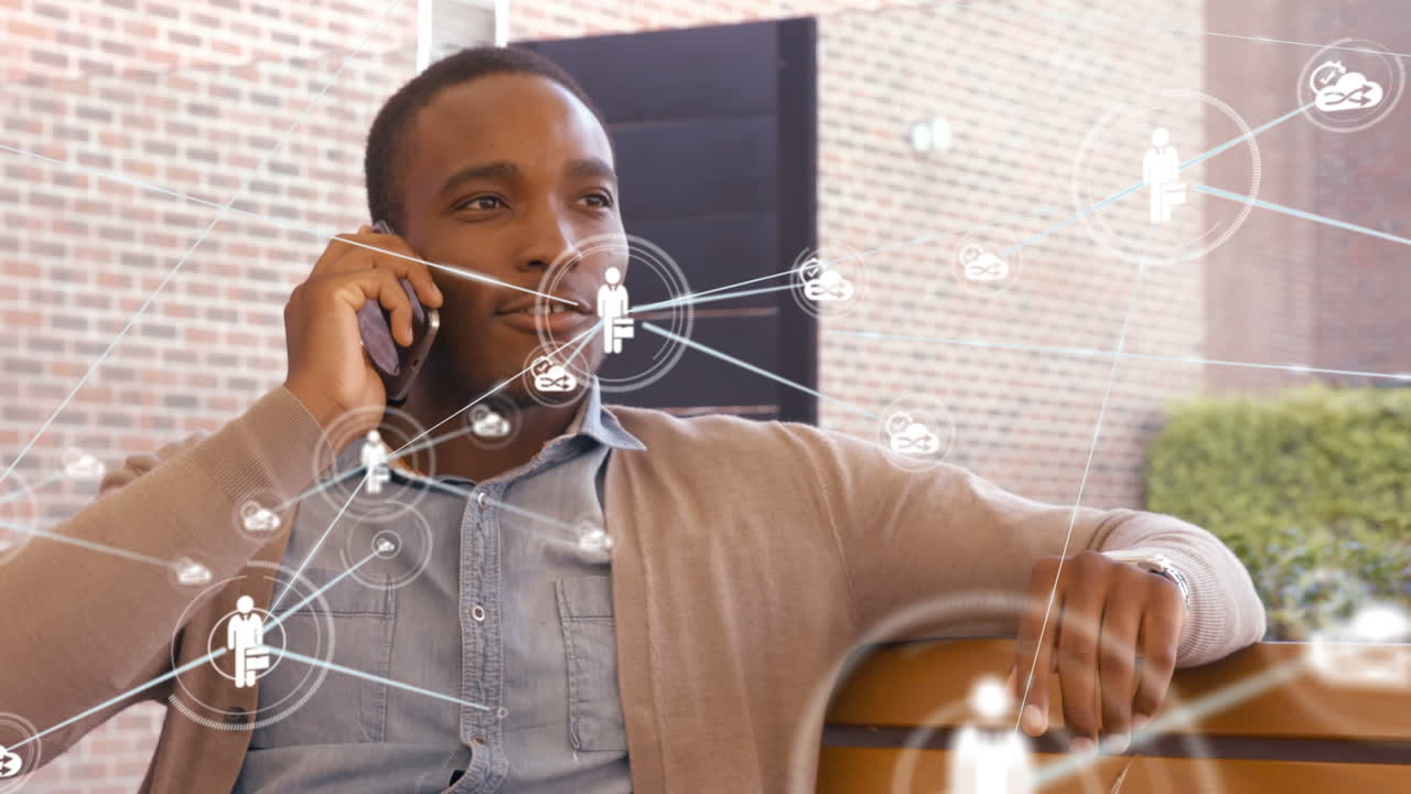 Animation of network of connections with icons over african american businessman using smartphone