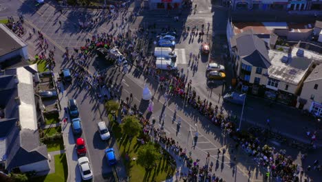 town parade with crowds and cars