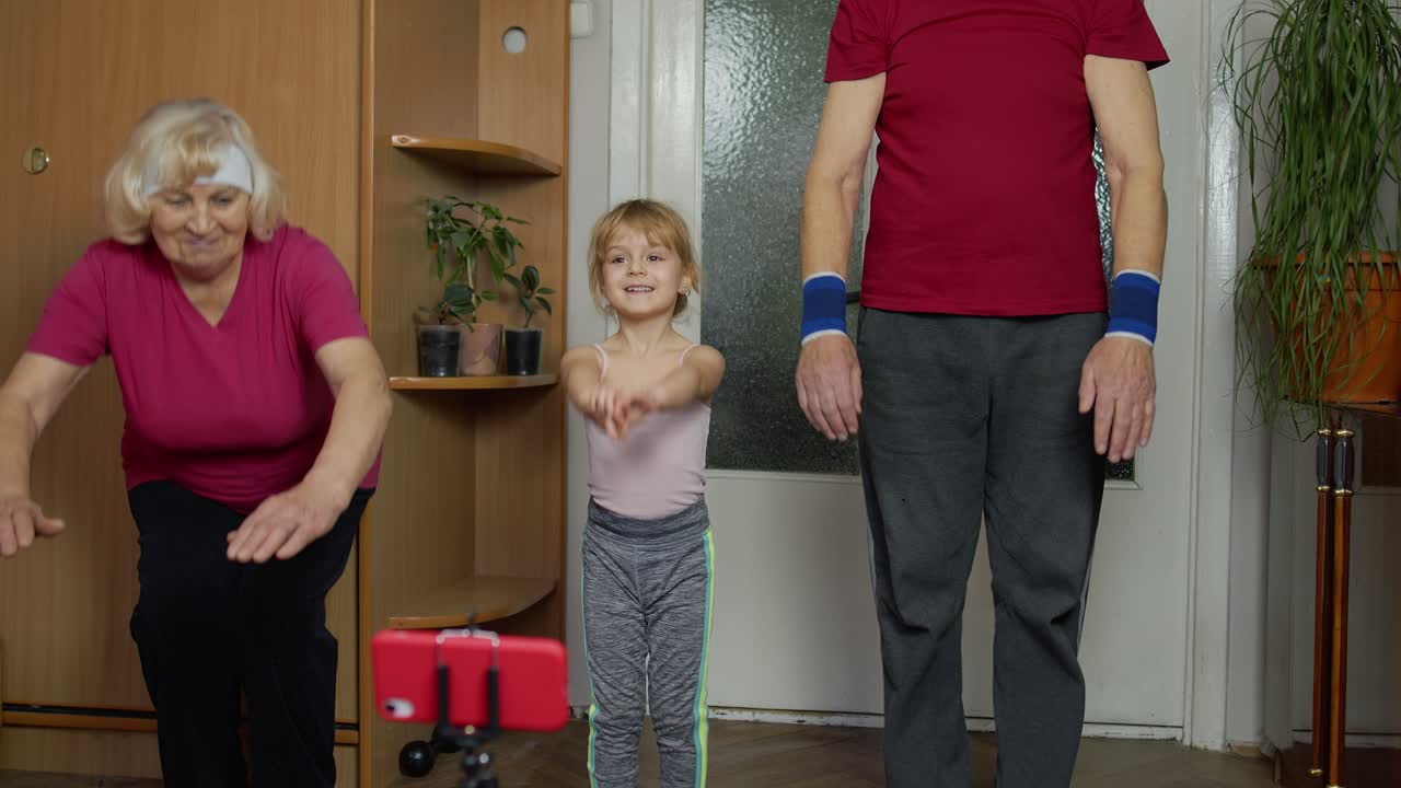 가족 운동: 할아버지, 할머니와 손녀가 집에서 함께 운동합니다.