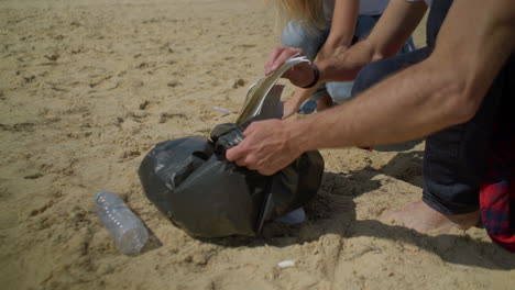 Cropped-shot-of-couple-picking-garbage-on-beach