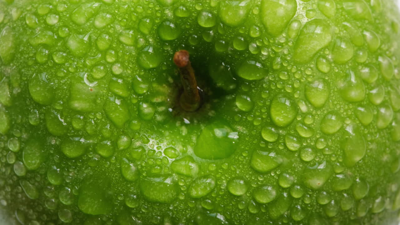Primo piano di una deliziosa mela verde fresca e croccante con goccioline d'acqua.