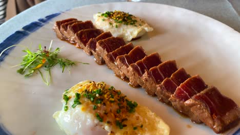 atún asado en una sartén con dos huevos asados con cebolla fresca y microgreens en un restaurante de lujo, comida deliciosa, atún, tiro de 4k