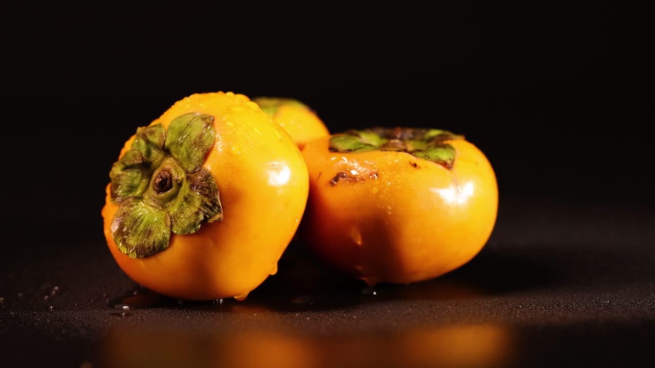 dos caqui girando en una superficie oscura