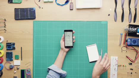 Top-view-woman-software-engineer-using-smartphone-touchscreen-at-desk-from-above---Red-Epic-Dragon