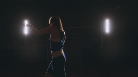 Entrenando-A-Una-Hermosa-Boxeadora-Dando-Golpes-En-Un-Cuarto-Oscuro.-Disparo-De-Cámara-Steadicam.-Preparación-Para-La-Autodefensa-Y-La-Lucha-En-El-Ring