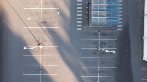 aerial view empty grocery store parking lot with white car driving by