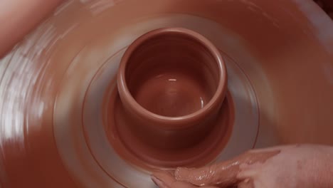 shaping a cup on a spinning pottery wheel