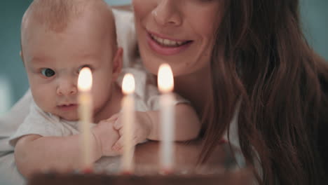 woman with baby blowing candles on birthday cake. family birthday party