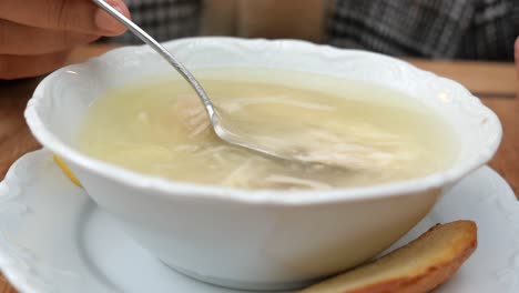 a bowl of chicken soup with a slice of bread