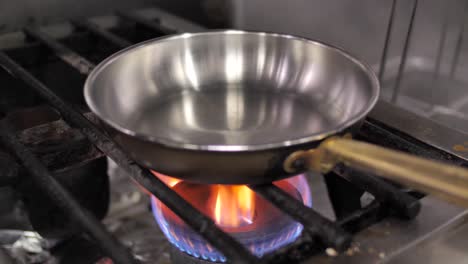 chef irreconocible poniendo una sartén en la estufa de gas encendida, cerrar