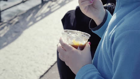 Close-up-of-little-girl-with-blue-jumper-nail-polish-and-teddy-bear-beside-her-holding-a-sundae-ice-cream-sitting-outdoor-4k