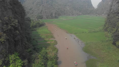 Flying-over-river-at-Ninh-Binh-surround-by-green-rice-fields-at-Vietnam,-aerial