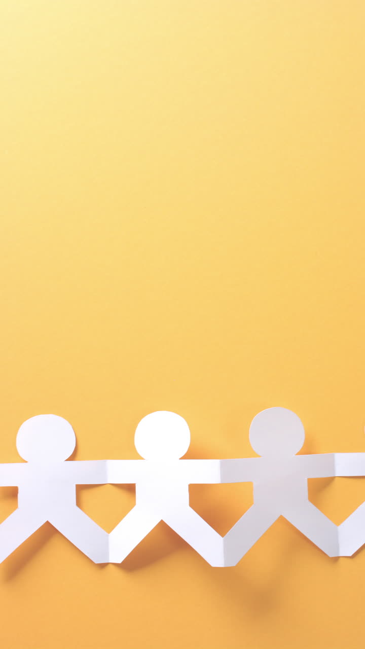 primer plano de personas con las manos hechas de papel blanco sobre fondo amarillo con espacio de copia