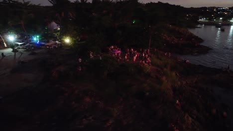 gente viendo la puesta de sol en el bar de la playa junto al mar con luces de colores disparadas con drones