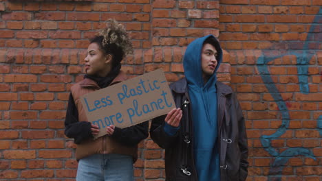 jovens ativistas masculinos e femininos americanos segurando cartazes de papelão durante um protesto contra as mudanças climáticas