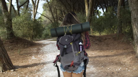 chica de senderismo caminando por el sendero del bosque para acampar