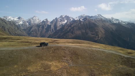 Schwarzes-Auto,-Das-Auf-Der-Straße-Mit-Dem-Kaukasus-Im-Hintergrund-Fährt,-Swanetien,-Georgien