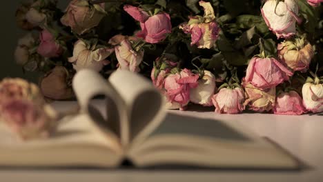 un ramo de rosas marchitas y un libro abierto con corazón