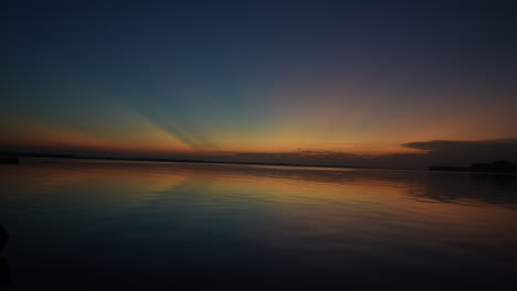 wide beautiful timelapse of the sky and the sun at sunset above a wide river.