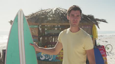 hombre caucásico sosteniendo su tabla de surf