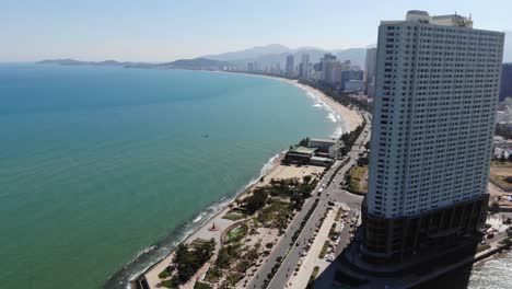 Vista-Aérea-Del-Edificio-Alto-Del-Hotel-Y-La-Costa-Con-El-Paisaje-Urbano-De-Nha-Trang-Durante-El-Hermoso-Día-Soleado-De-Verano-En-Vietnam