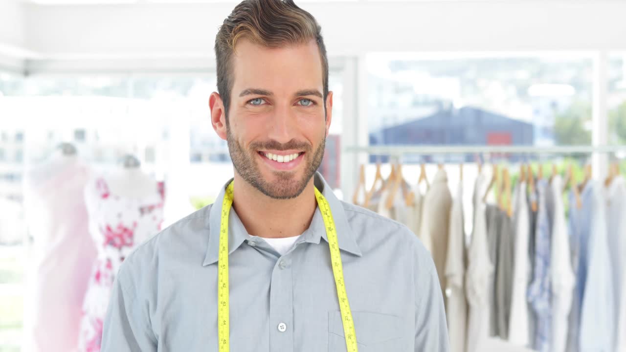 Estilista bonito segurando uma tesoura sorrindo para a câmera