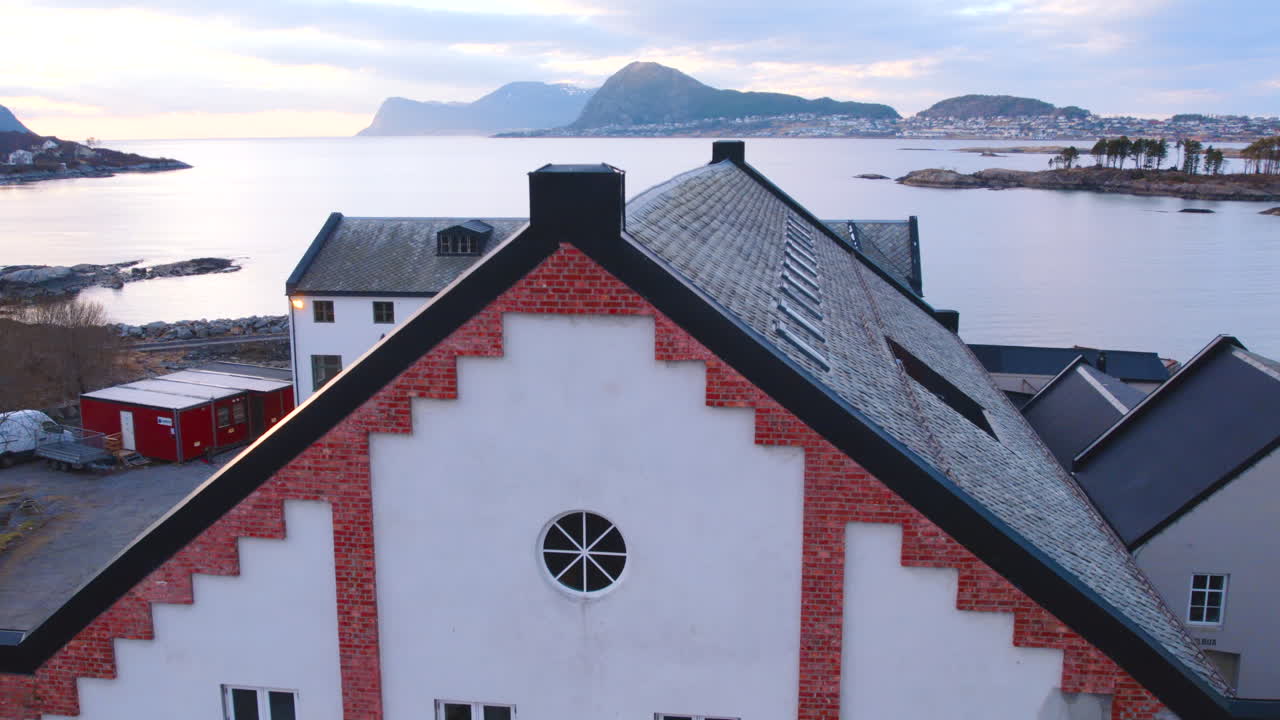 Dron ascendiendo mostrando una fábrica renovada y revelando un fiordo noruego