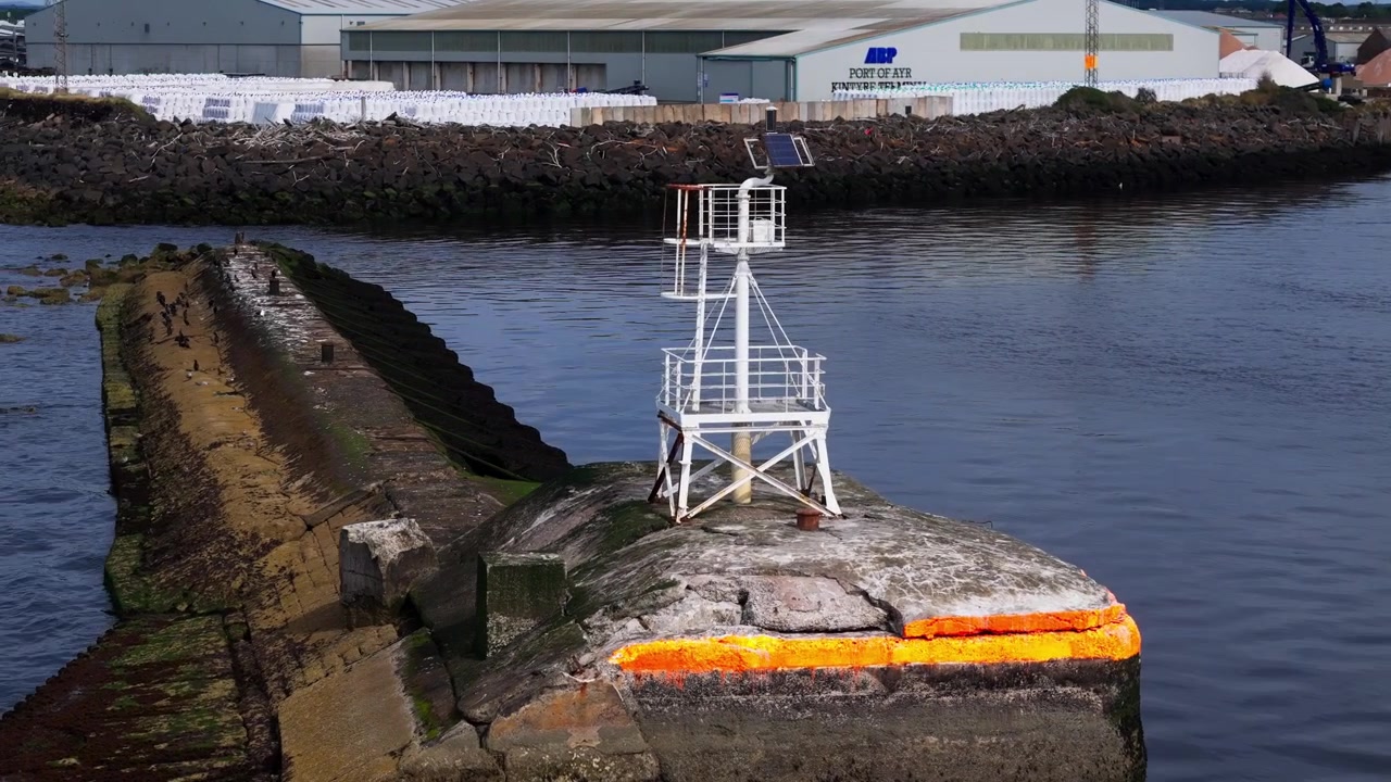Vista aérea, pequeña baliza de navegación en el muro del puerto en el paseo marítimo de Ayr, Escocia, marcando el límite del agua dentro del puerto en funcionamiento