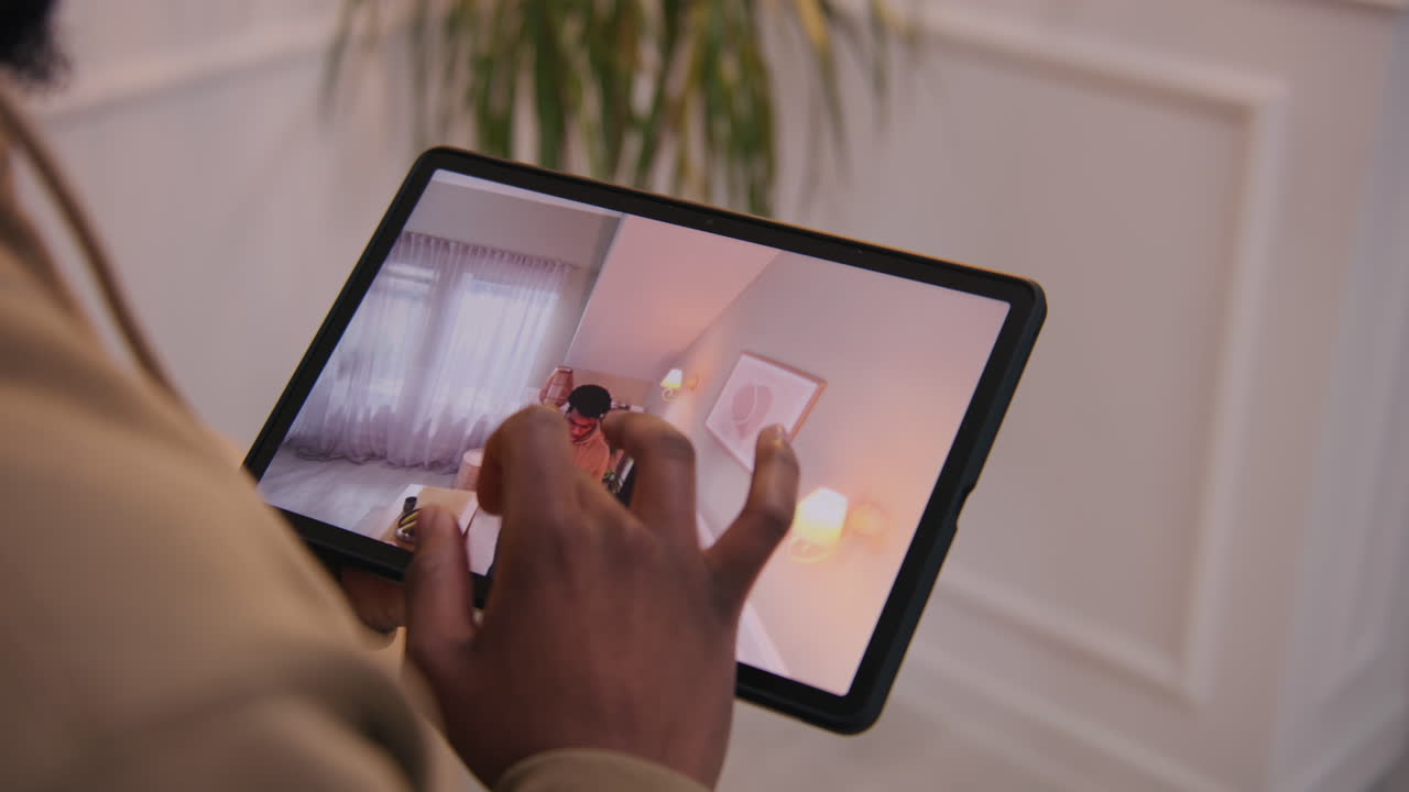 persona que usa una tableta para ver una llamada de video en una sala de estar.