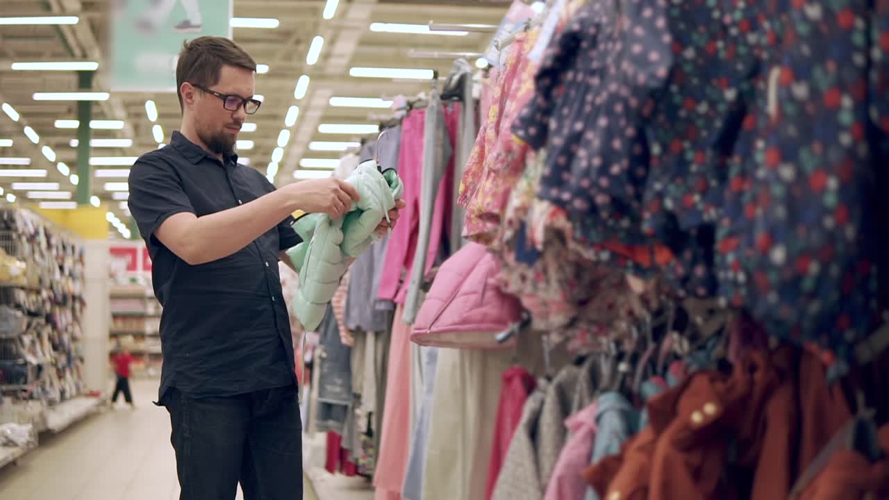 Uomo che acquista giacche per bambini in un grande magazzino