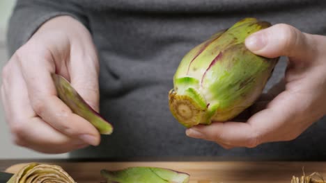 Woman-cleaning-artichokes.-Cooking-process-at-the-kitchen.-Closeup