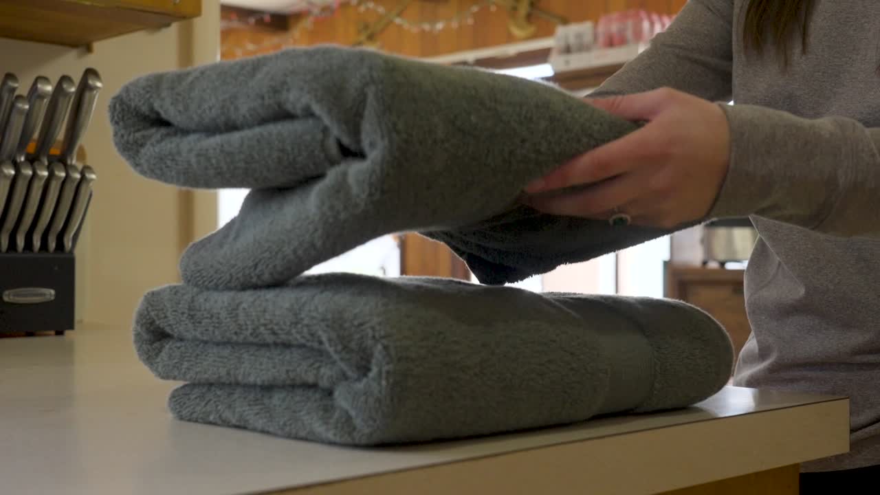 Folding soft cotton towels and placing them in a stack on the counter