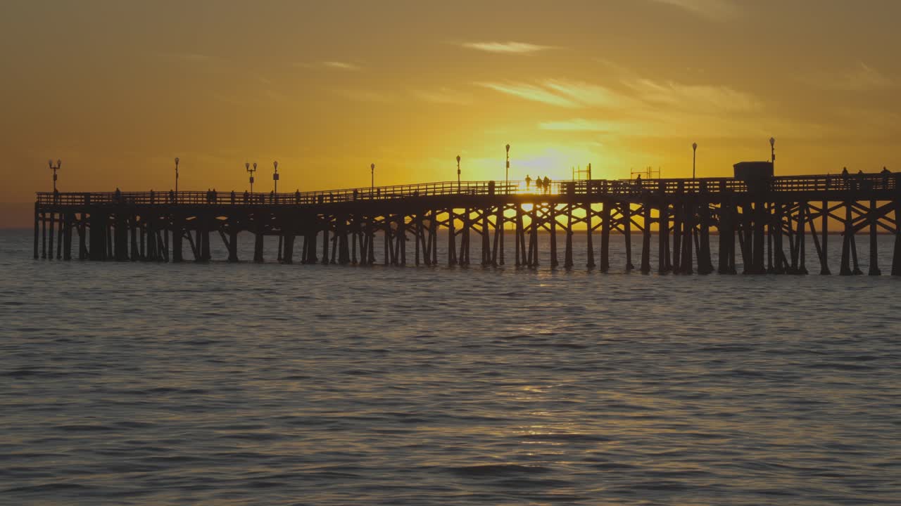 A peaceful pier in Long Beach with ocean waves, sunset, warm light, and serene vibes
