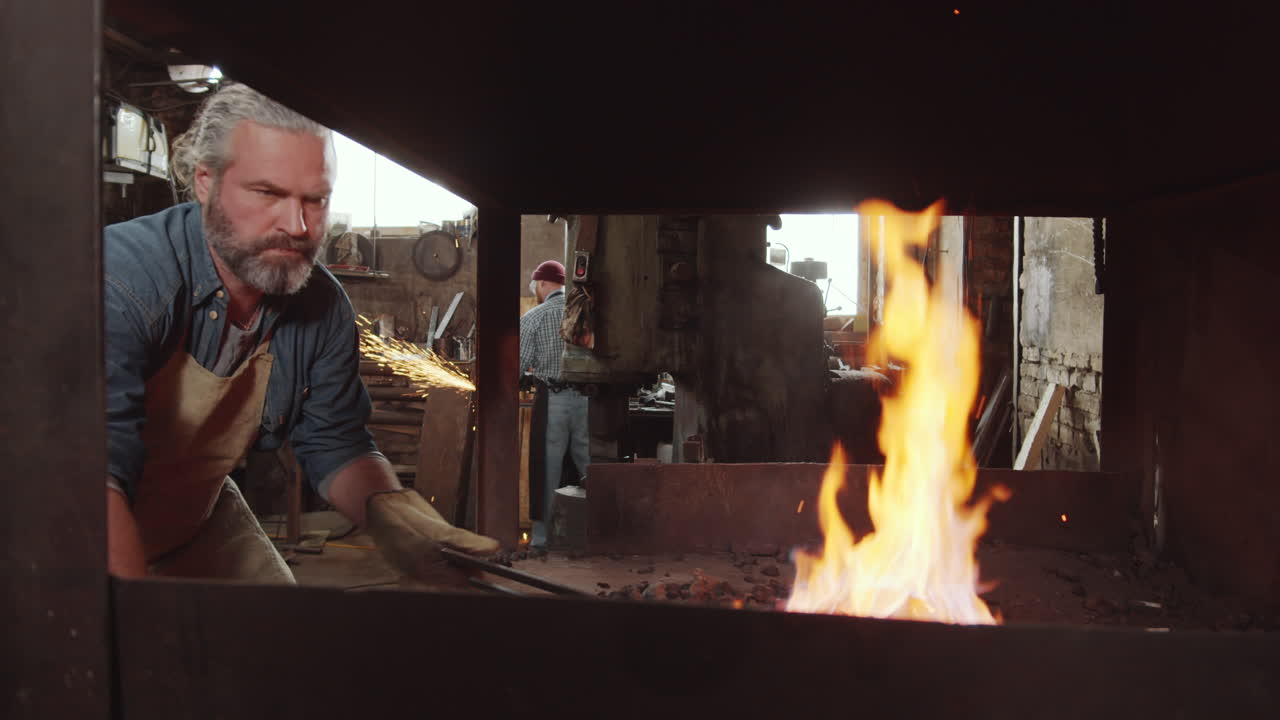 старший кузнец разжигает огонь в кузнице