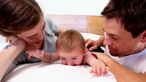 happy parents lying with their cute baby son on bed