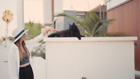 woman interacting with a black cat outdoors