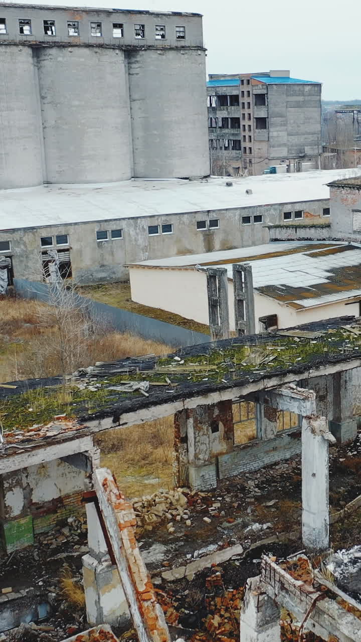Aerial view of an old factory ruined building with debris and broken bricks with collapsed roof. Old industrial building for demolition. Vertical video