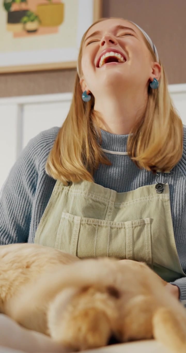 Giovane donna che ride mentre gioca con cuccioli di golden retriever