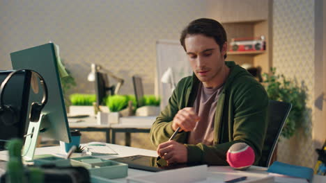 pensive creator watching computer screen at office. freelance man using tablet