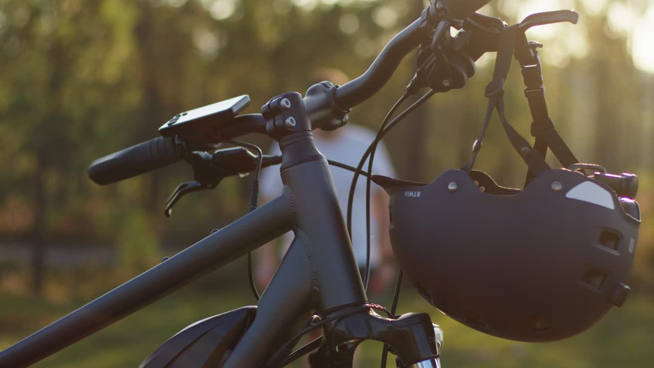 primer plano de un casco colocado en el manillar de una bicicleta eléctrica mientras un hombre se acerca, preparándose para su viaje.