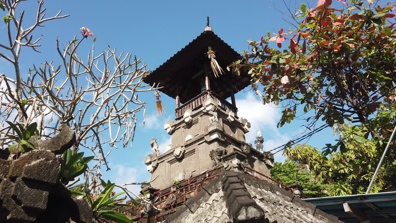 Low angle view of Balinese hindu temple around colorful tree flowers and skyline