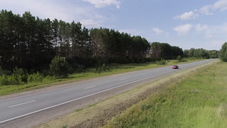 country road with red car and forest