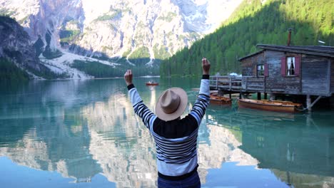 rear shot of man with hat celebrating near scenic lago di braies