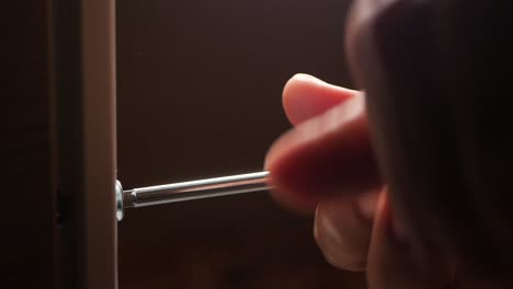 person using a screwdriver to fix a door