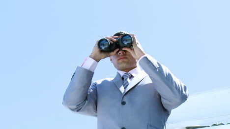 high angle of businessman looking through binoculars