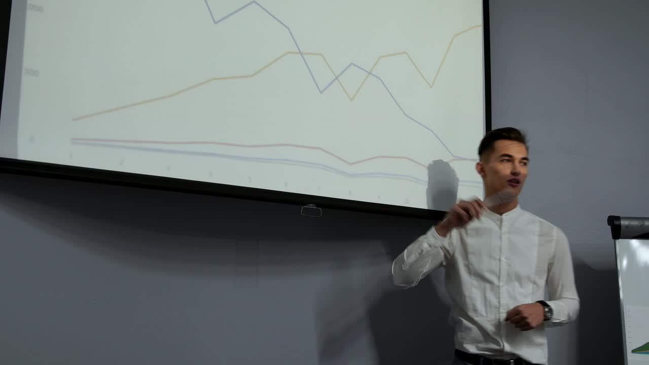 un joven empleado de la empresa con una camisa blanca informa sobre el progreso del trabajo realizado durante el año pasado y los planes para el desarrollo del barrio ocupado en el diagrama del proyector en la oficina