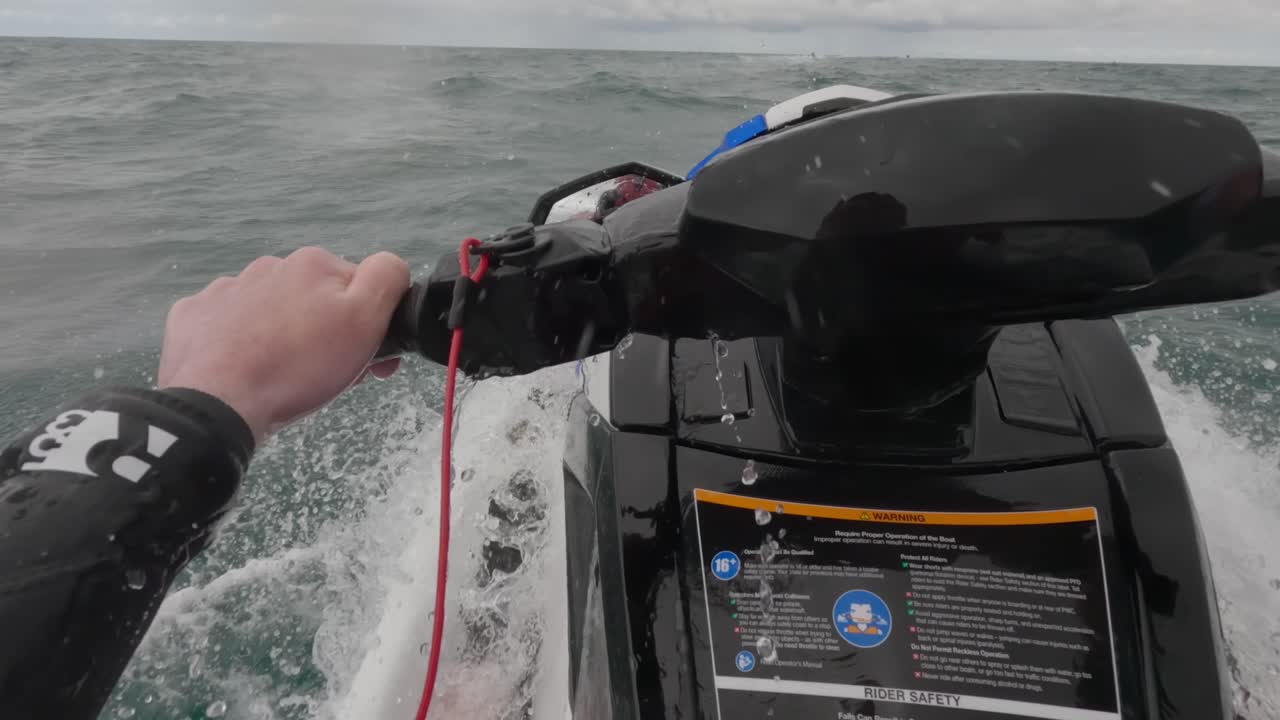 POV show of a jet skier riding slowly across choppy waves getting soaked